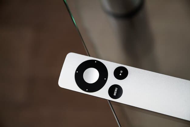 A close-up of the Apple TV 4K's Siri Remote, highlighting its sleek design and intuitive button layout. The background is a blurred image of the Apple TV 4K device connected to a modern TV.