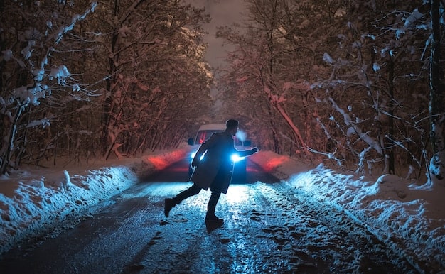 A still from Blade Runner 2049 featuring Ryan Gosling as K kneeling in the snow, his face illuminated by a soft blue light. The background is a blurred and desolate landscape, hinting at a post-apocalyptic environment.