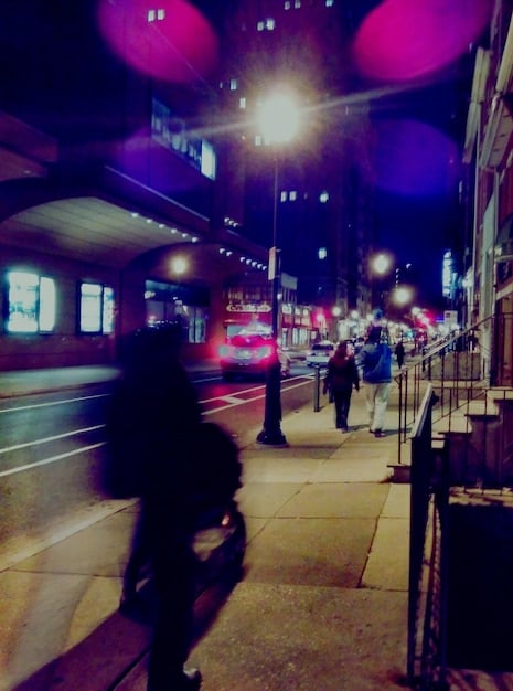 A movie scene showing a bustling city street with various sound effects visible as stylized icons (e.g., car horns, people talking, construction noises). The image visually represents the layering of sounds to create an immersive environment.