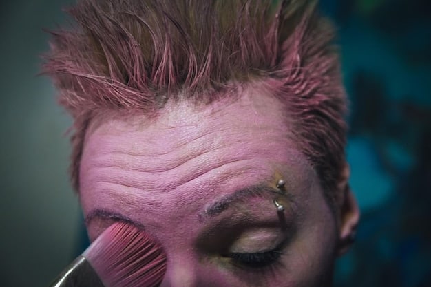 A close-up of a makeup artist applying detailed prosthetic makeup to an actor's face, transforming him into a creature or character. Various makeup tools and materials are visible, highlighting the intricate and hands-on nature of the process.