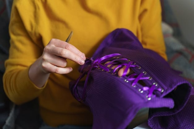 A close-up of a costume designer's hands meticulously sewing beads onto a dress in a dimly lit workshop. The garment is partially finished as the designer carefully hand-stitches intricate detailing, showing patience and precision.