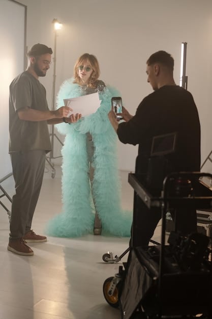 A film set with a director giving instructions to an actress wearing a period costume. The designer stands somewhat behind them, observing and making mental notes. The lighting is standard for a film set, and the atmosphere is professional and collaborative.