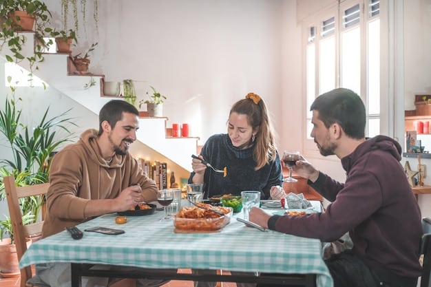A candid shot of Joey Graziadei sitting at a family dinner table during a hometown visit, engaged in a lively conversation with the contestant's parents and siblings. The atmosphere is warm and inviting, with the setting being a cozy dining room decorated with family photos.