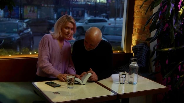 A dimly lit conference room with Shiv, Kendall, and Roman huddled around a table, looking at financial documents. Their faces are etched with worry and determination.