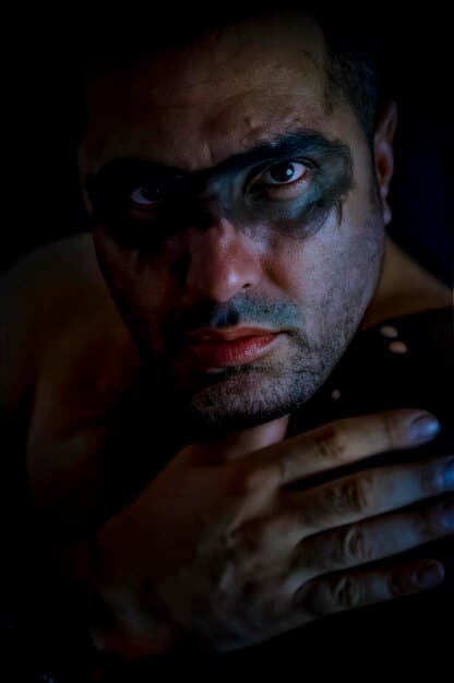 A close-up shot of Kendall Roy (Jeremy Strong) in a dimly lit room, his face reflecting a mixture of ambition and inner turmoil. He is holding a phone to his ear, suggesting a high-stakes business conversation or a tense personal call. The background is blurred, emphasizing his isolation and the weight of his responsibilities.