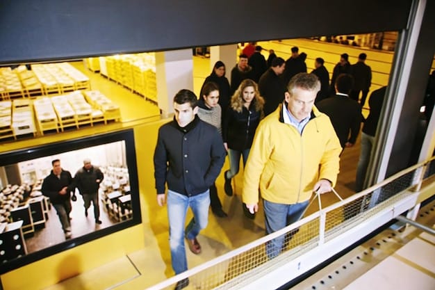 A movie theater lobby bustling with activity, featuring a large digital display showcasing various movie posters and upcoming release dates for films in early 2025. The scene captures the excitement and anticipation of moviegoers.