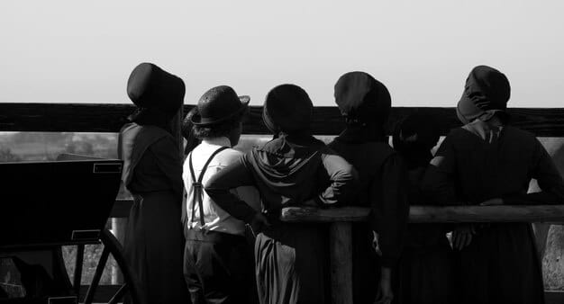 A black and white image depicting a group of striking writers or actors holding signs outside a studio lot. The image should evoke a sense of solidarity and determination.