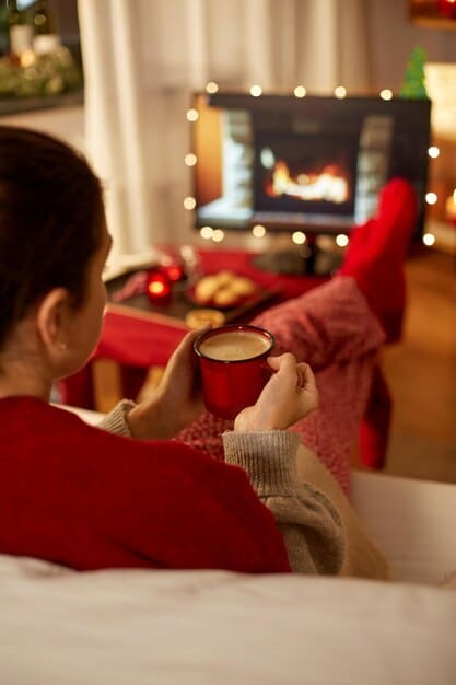 A cozy living room setup with a brightly lit Christmas tree, a fireplace, and a family watching a holiday movie with popcorn and blankets, capturing the warmth and togetherness of the holiday season.