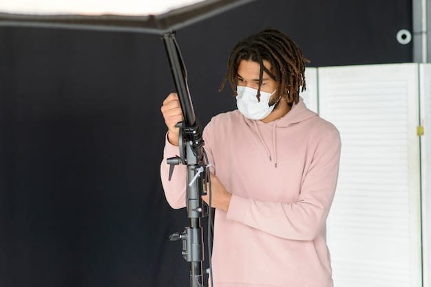A masked film crew member adjusting camera equipment on a movie set, showcasing the new normal of enhanced health and safety protocols during production.