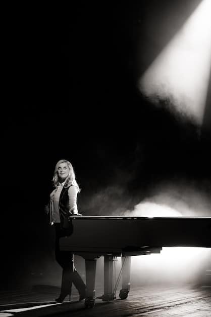 A black and white photograph of a legendary musician performing on stage in front of a massive crowd. The musician is playing an electric guitar with passion, and the audience is cheering wildly. The image captures the energy and excitement of a live concert.