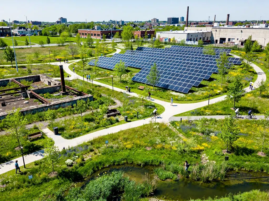 Revitalized brownfield site transformed into a green park with solar panels and natural landscaping, symbolizing climate solution success.